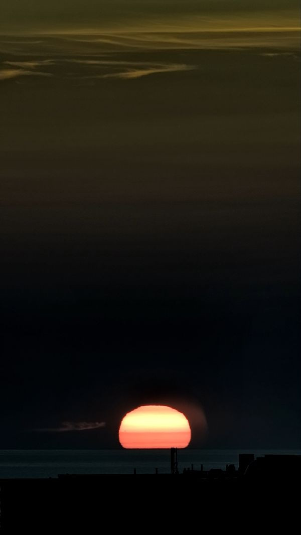 The distorted Sun sets below the horizon. - Astrophotography